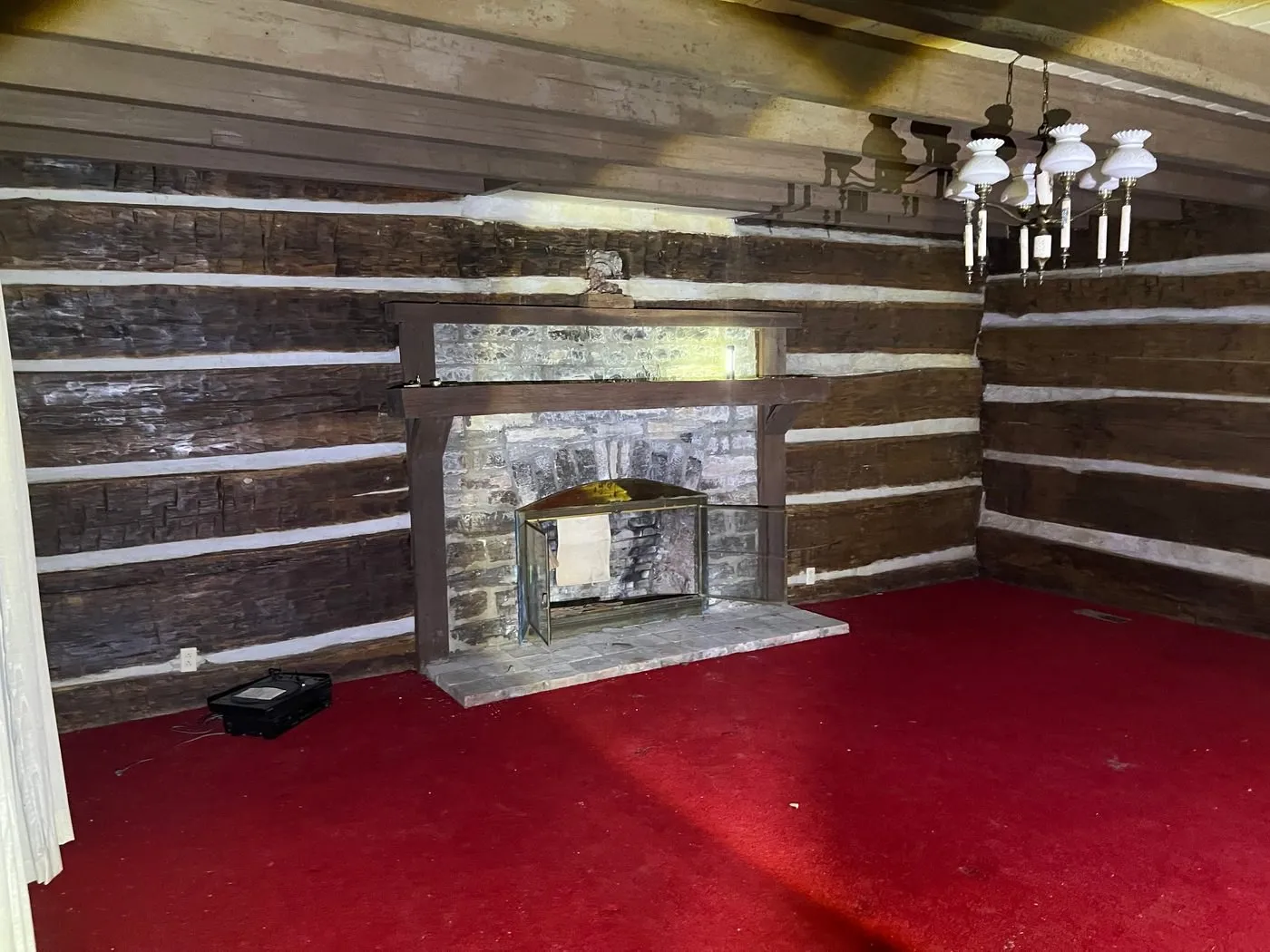 The log walls and stone fireplace inside the Latimer House in May 2025, red carpet on the floor