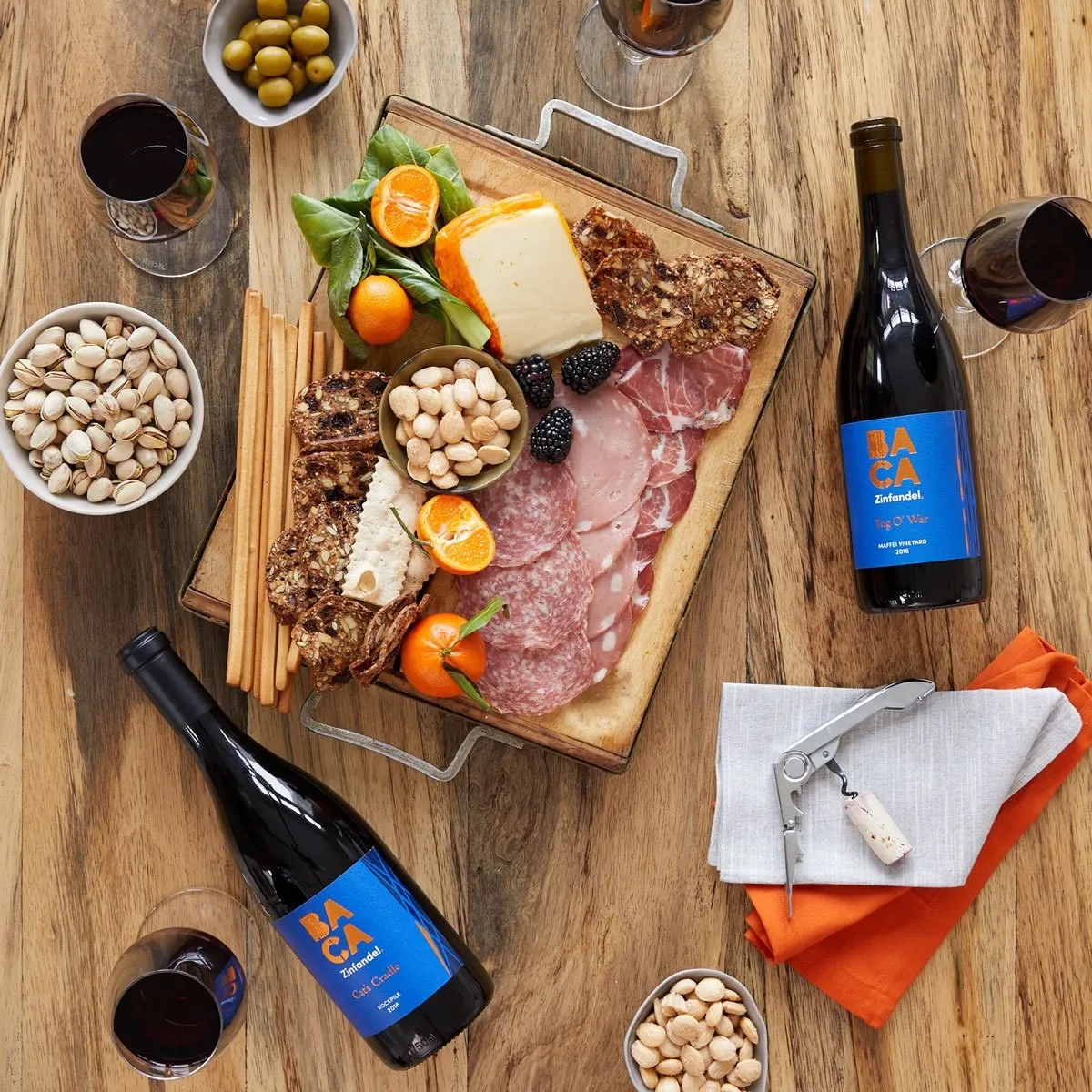 A charcuterie board with two bottles of BACA